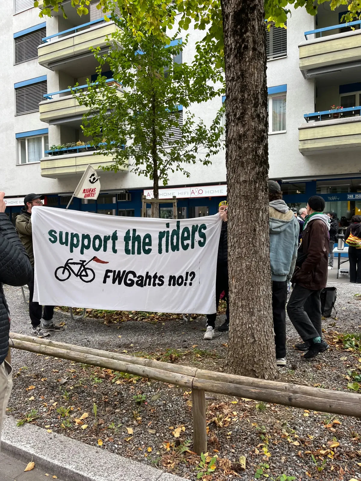 Die «Velo-Riders» wünschen sich Unterstützung. Man sieht protestierende Kurierinnen und Kuriere vor einem Haus.